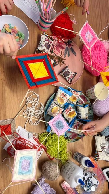 Bunte Bastelarbeiten auf einem Tisch, darunter Garn, Bilder und Bastelmaterialien.